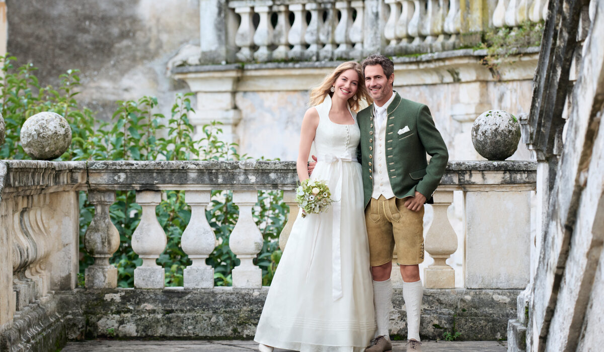 Trachtenhochzeit Pärchen in Hochzeitskleid, grüner Trachtenjacke und Hirschlederhose