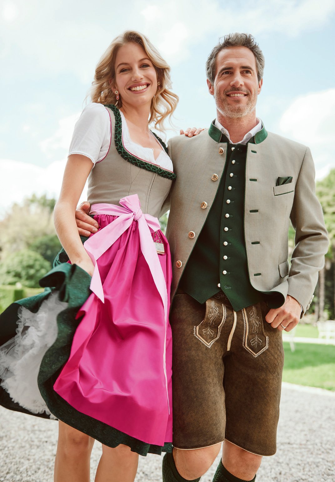 Vertrautes Paar – sie in beigem Dirndl mit rosa Satinschleife, er in dunklem Trachtenjanker und Lederhose – Wimmer schneidert