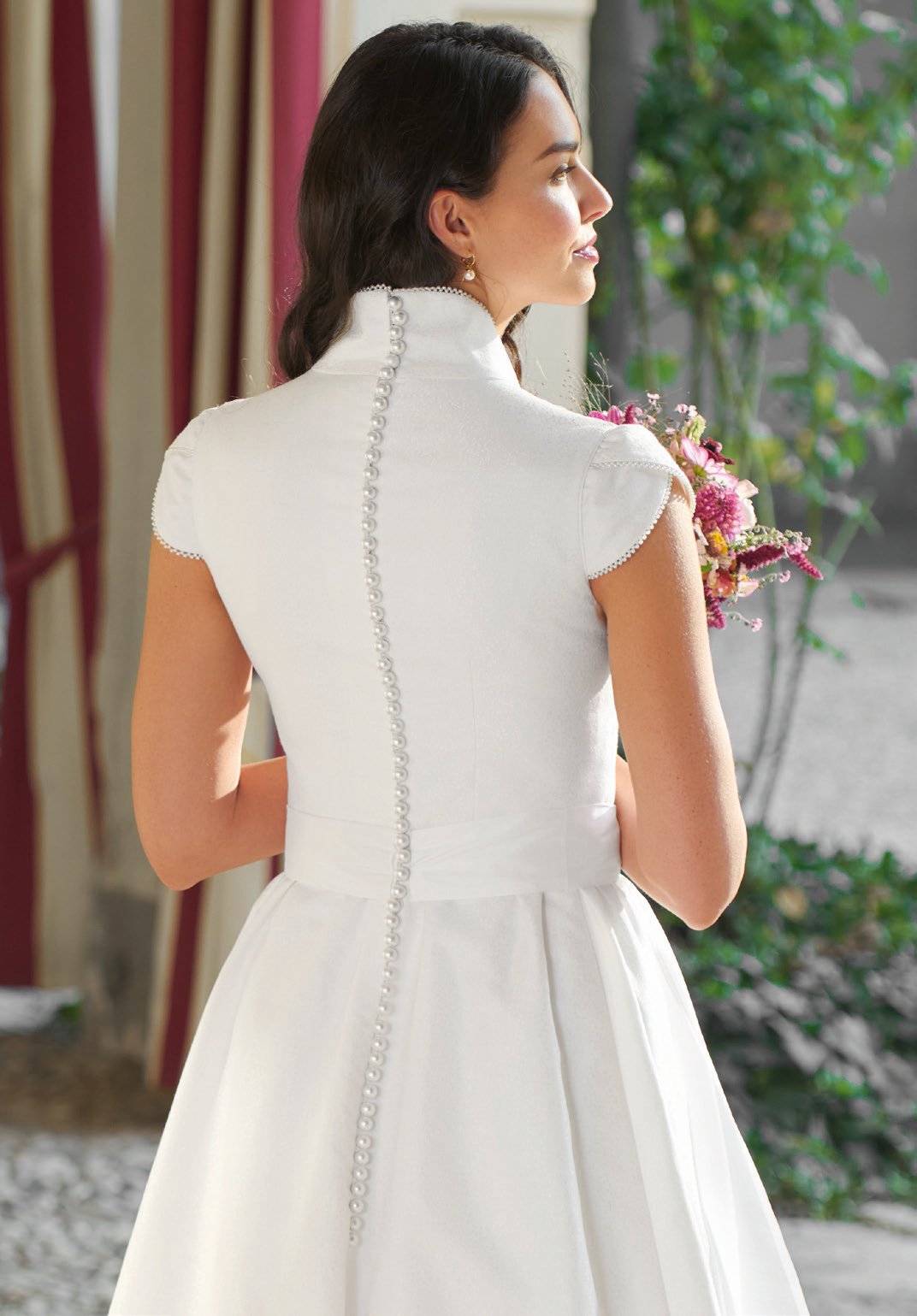 Rückenansicht eines weißen Hochzeitskleids mit Perlknöpfen und steifem Kragen – Detailaufnahme Wimmer schneidert