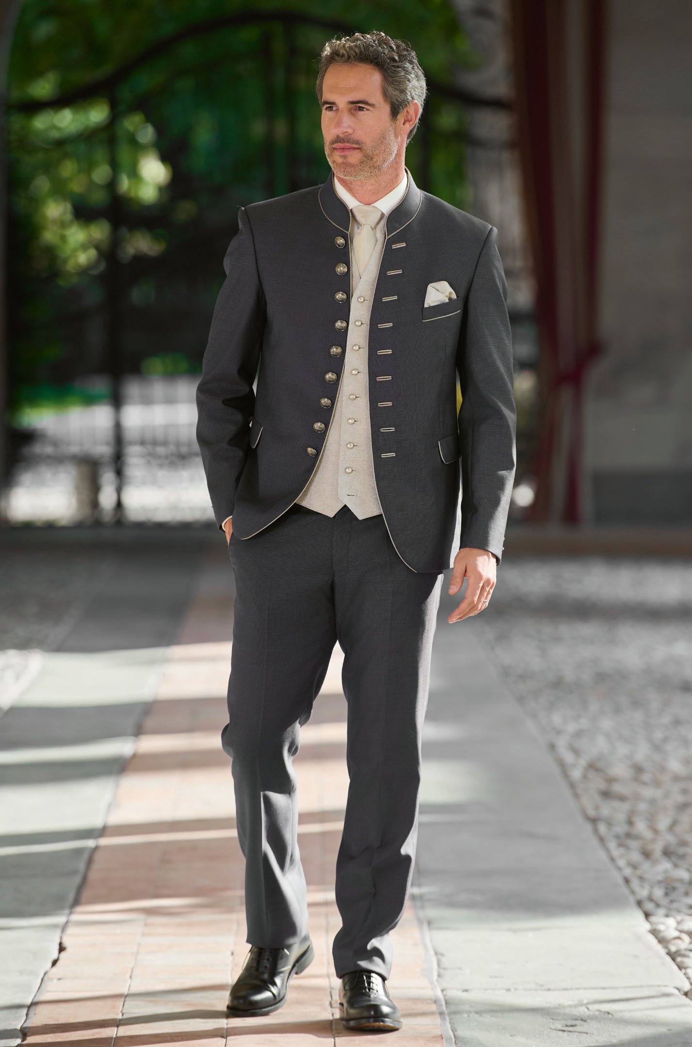 Herr in anthrazitfarbenem Trachtenanzug mit silberner Brokatweste und Messingknöpfen im Villenbogen – Wimmer schneidert