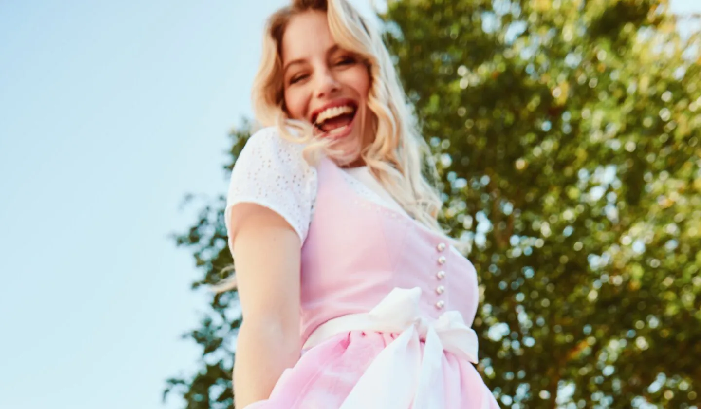 Frau mit strahlendem Laecheln in Rosa Tracht, Nahaufnahme