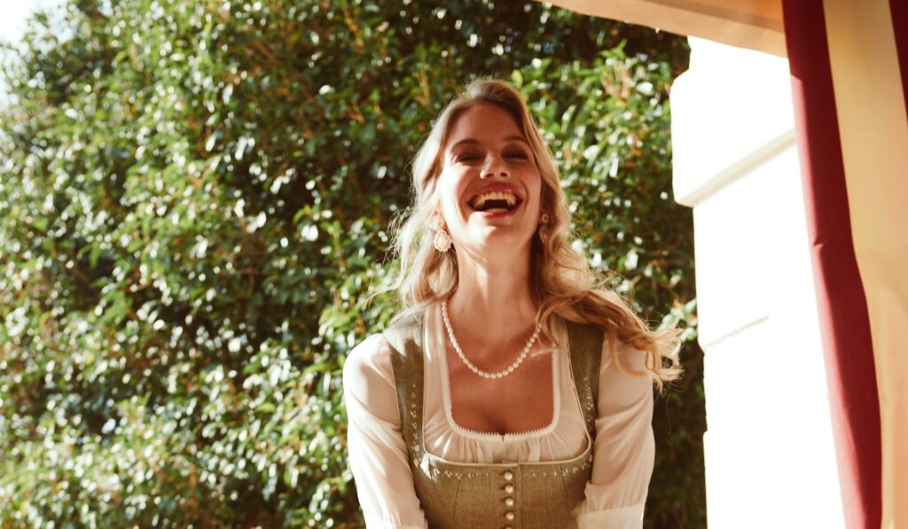 Frau im cremefarbenen Dirndl mit Blumenstrauß, Hochzeitstracht-Stil