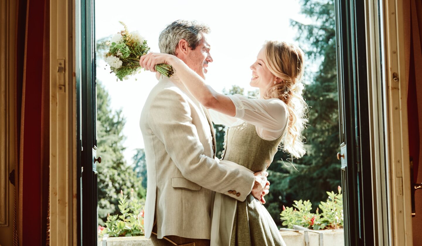 Romantisches Paar in Tracht in eleganter Türöffnung mit warmem Naturlicht von außen