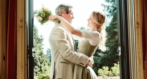 Romantisches Paar in Tracht in eleganter Türöffnung mit warmem Naturlicht von außen