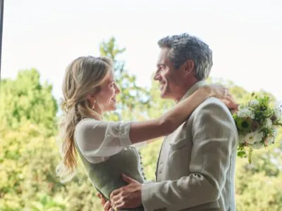 Trachtenpaar auf sonniger Terrasse, Mann in Jacke und Frau im Dirndl, Gartenszenario