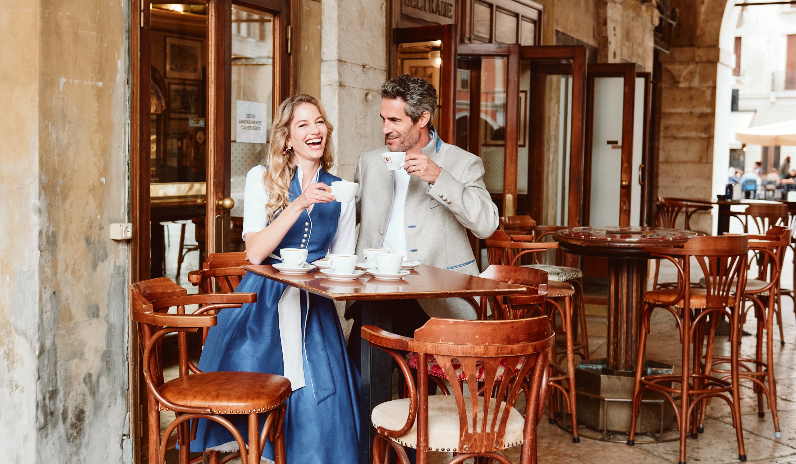 Frau und Mann in Tracht genießen Kaffee unter historischen Arkaden in Treviso